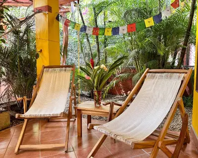 two chairs and a table on a patio with plants at The Inner Light Yoga Lodge in Sámara