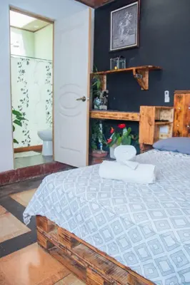 a bedroom with a bed with a wooden frame at Gardens House, Airport Juan Santamaría, Alajuela, San José in Alajuela City