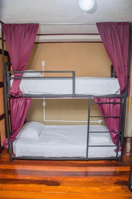two bunk beds in a room with purple curtains at Gardens House, Airport Juan Santamaría, Alajuela, San José in Alajuela City