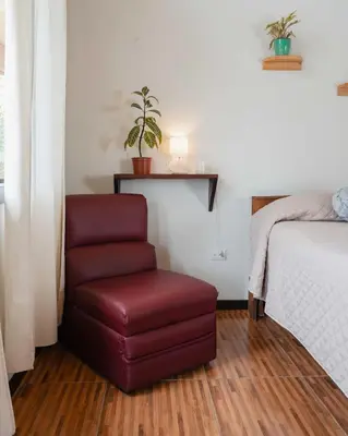 a bedroom with a red chair next to a bed at Cabañas La Hacienda in San Pablo