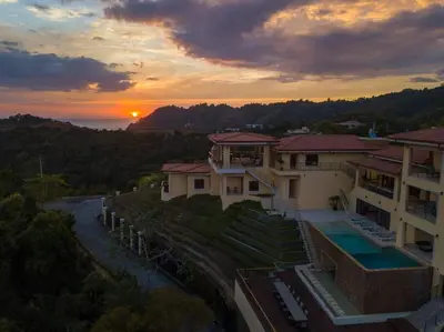 a sunset view of a house and a river at Casa Amarillo Jaco Beach Costa Rica in Jacó