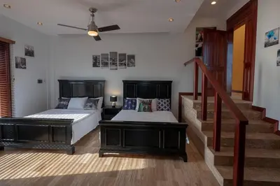 a bedroom with two beds and a staircase at Casa Amarillo Jaco Beach Costa Rica in Jacó
