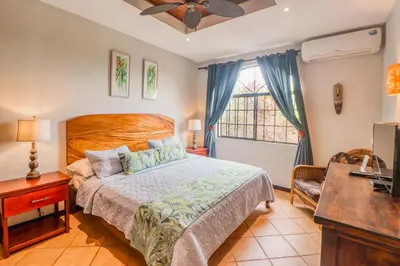 a bedroom with a bed and a desk and a television at Casa Mimosa Poolside in Playa Flamingo