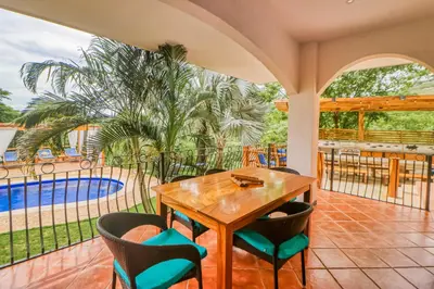 a patio with a table and chairs and a pool at Casa Mimosa Poolside in Playa Flamingo