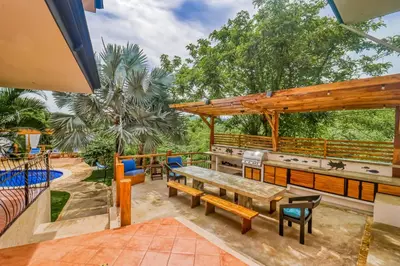 an outdoor patio with a table and a grill at Casa Mimosa Poolside in Playa Flamingo