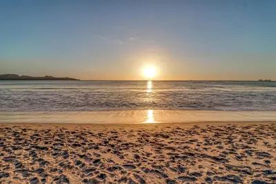 a sunset on a beach with the ocean at Casa Mimosa Poolside in Playa Flamingo