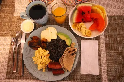 a table with a plate of food and a bowl of fruit at F&M Guesthouse in San José