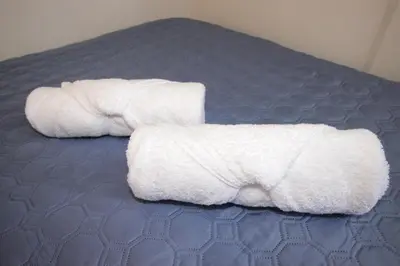 two white towels are laying on a bed at F&M Guesthouse in San José