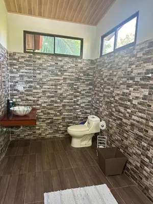a bathroom with a toilet and a brick wall at Villas In Sueño in Manuel Antonio