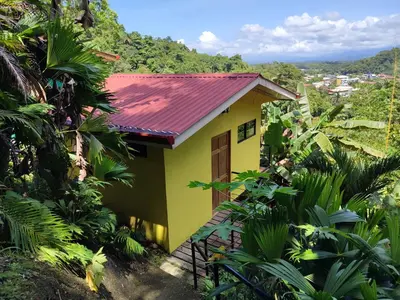 a yellow house with a red roof in the jungle at Villas In Sueño in Manuel Antonio