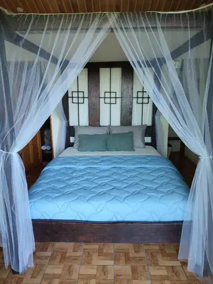 a bed in a room with blue sheets and curtains at Villas In Sueño in Manuel Antonio