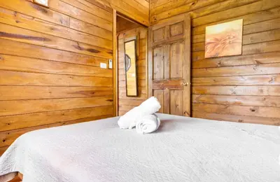 a bedroom with a white bed with wooden walls at Whale Melody Marabi in Uvita