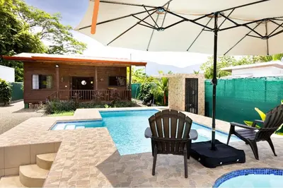 a swimming pool with two chairs and an umbrella at Whale Melody Marabi in Uvita