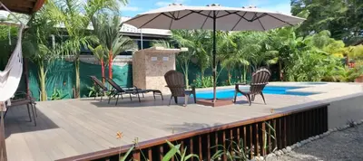 a deck with chairs and an umbrella next to a pool at Whale Melody Marabi in Uvita