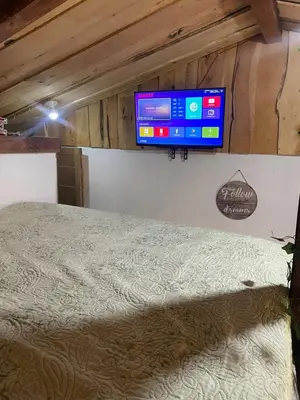 a bedroom with a bed and a television on the wall at Poas Volcano Rooms in Fraijanes