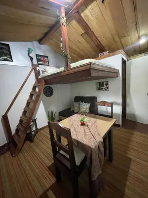 a living room with a table and a loft bed at Poas Volcano Rooms in Fraijanes