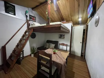 a room with a table and a staircase in a tiny house at Poas Volcano Rooms in Fraijanes
