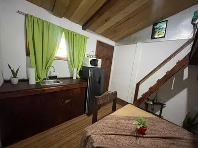 a small kitchen with a table and a green curtain at Poas Volcano Rooms in Fraijanes
