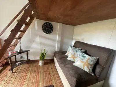 a living room with a couch and a clock on the wall at Poas Volcano Rooms in Fraijanes