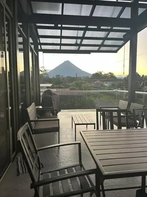 a porch with tables and chairs and a view of a mountain at Brisas del Volcán BnB in Fortuna