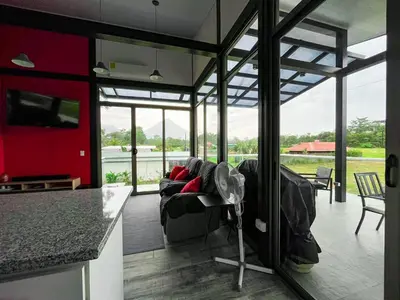a living room with a couch and a kitchen with windows at Brisas del Volcán BnB in Fortuna