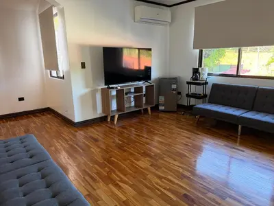 a living room with a couch and a flat screen tv at Zeus Guest house & Car Rental Free SJO Airport Shuttle-NATIONWIDE PRÍVATE SHUTTLE SERVICE in La Garita