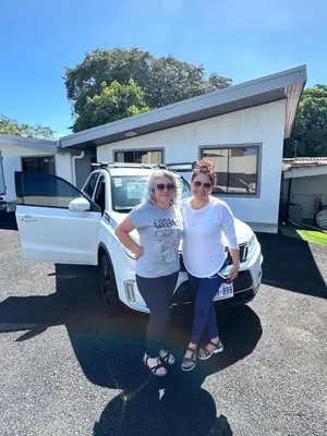 two women are standing next to a white truck at Zeus Guest house & Car Rental Free SJO Airport Shuttle-NATIONWIDE PRÍVATE SHUTTLE SERVICE in La Garita