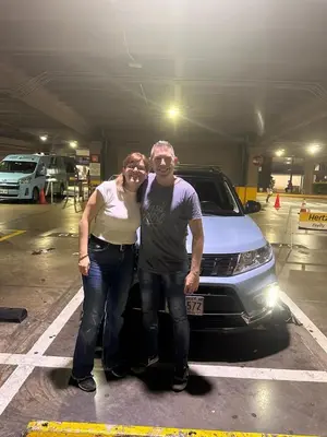 a man and a woman standing next to a car at Zeus Guest house & Car Rental Free SJO Airport Shuttle-NATIONWIDE PRÍVATE SHUTTLE SERVICE in La Garita