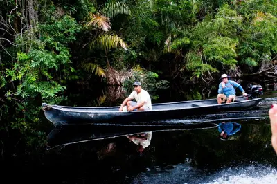 two men sitting in a boat on a river at Turtle Beach Lodge in Tortuguero