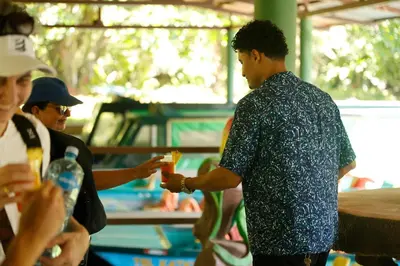 a man holding a drink in a crowd of people at Turtle Beach Lodge in Tortuguero