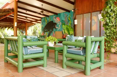 a group of green chairs and tables on a patio at Turtle Beach Lodge in Tortuguero