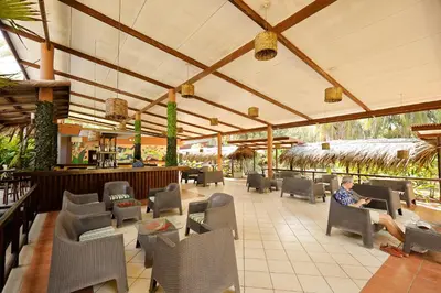 a man sitting in a chair in a restaurant at Turtle Beach Lodge in Tortuguero