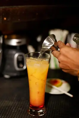 a person is pouring a spoon into a drink at Turtle Beach Lodge in Tortuguero