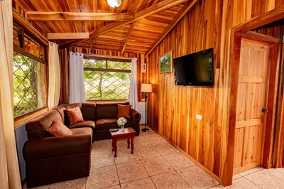 a living room with a couch and a flat screen tv at Cabañas La Pradera in Monteverde Costa Rica
