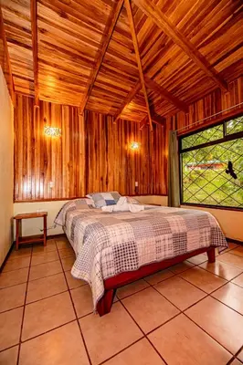 a bedroom with a bed in a wooden room at Cabañas La Pradera in Monteverde Costa Rica