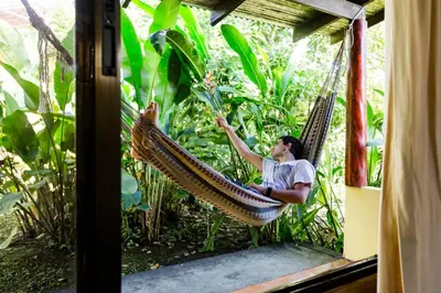 a man sitting in a hammock in a garden at Catarata Eco Lodge in Fortuna