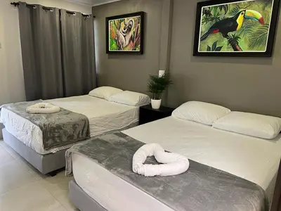 a room with three beds and a bird picture on the wall at La Posada del Mar in Dominical
