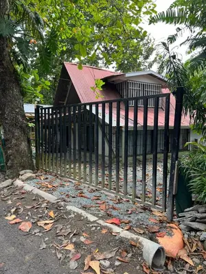 a black fence in front of a house with leaves at La Posada del Mar in Dominical