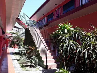 a staircase leading up to a red building with plants at ECONOMiKA in Jacó