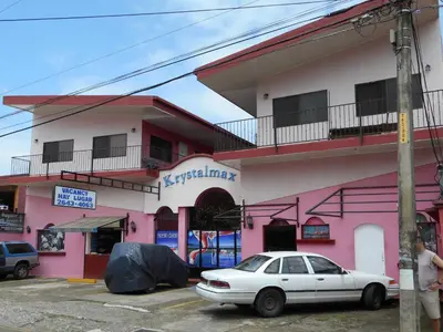 a white car parked in front of a pink building at ECONOMiKA in Jacó