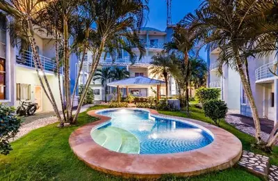 a swimming pool in front of a building with palm trees at Villa Verde II #30 in Tamarindo
