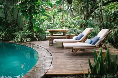 a patio with two lounge chairs and a swimming pool at Sueño del Mar Beachfront Hotel in Tamarindo