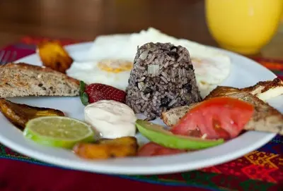 a plate of food with meat and vegetables on a table at Sueño del Mar Beachfront Hotel in Tamarindo
