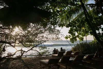 two people sitting in chairs on the beach at Sueño del Mar Beachfront Hotel in Tamarindo