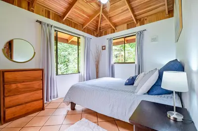a bedroom with a bed and two windows at Bromelia House in San Gerardo