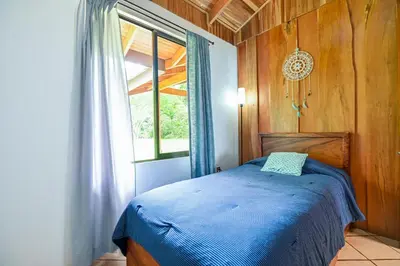 a bedroom with a blue bed and a window at Bromelia House in San Gerardo