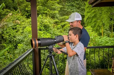 a man and a boy looking through a telescope at Bromelia House in San Gerardo