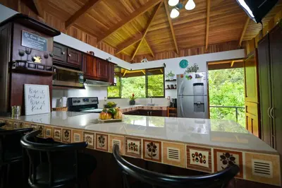 a large kitchen with a large counter with chairs at Bromelia House in San Gerardo