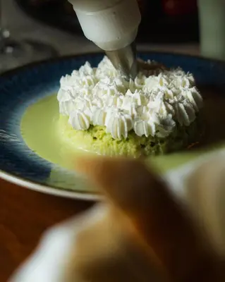 a person sprinkling whipped cream on top of a pie at Vayu Retreat Villas in Coronado