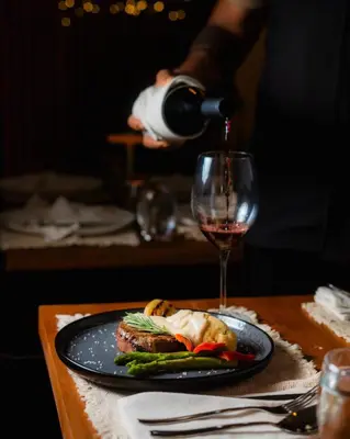 a person pouring a glass of wine over a plate of food at Vayu Retreat Villas in Coronado